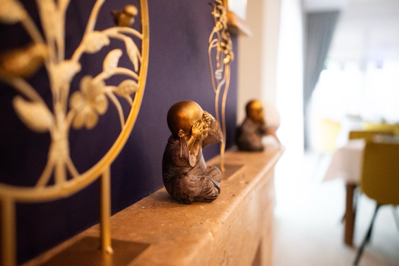 Detaliu de decor: figurine aurii pe polița de piatră, în fața peretelui violet